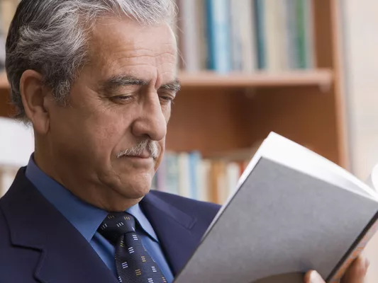 Man in suit reading book in library